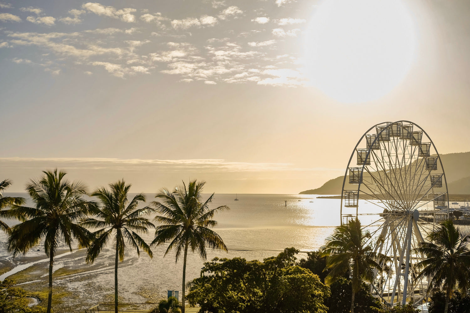 Sonnenuntergang in Cairns Australien mit dem Riesenrad und dem Hafen vor dem Meer