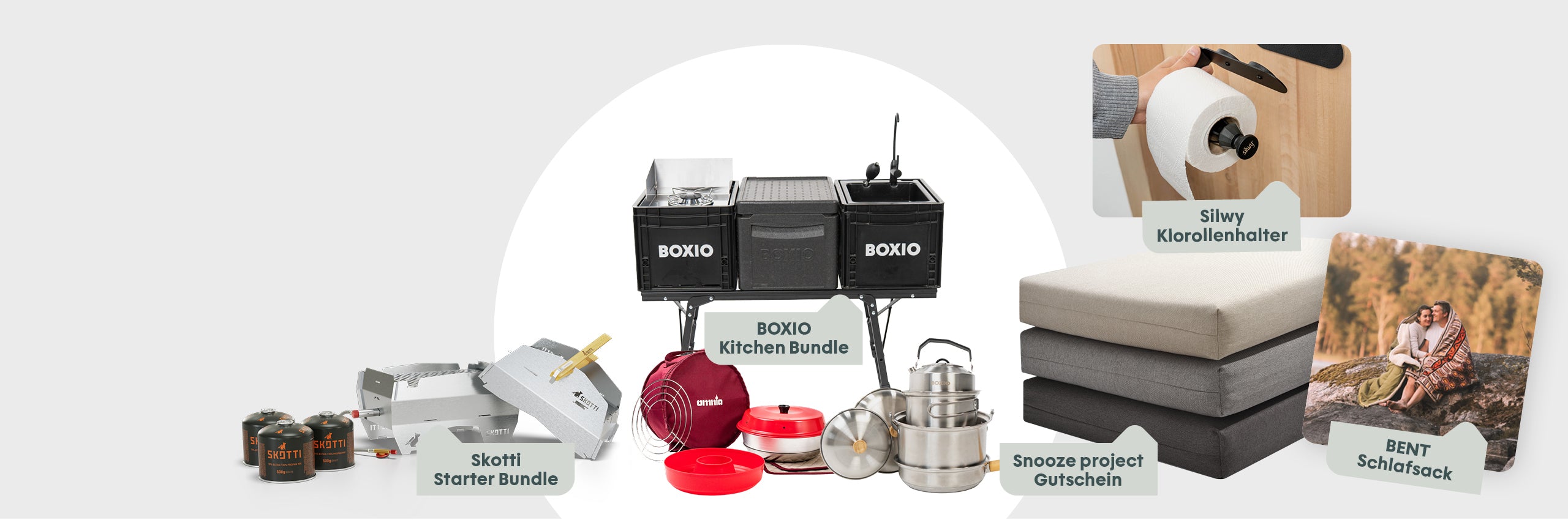 Verschiedene Campingprodukte, darunter Kochutensilien, Schlafsack, Gutschein und Küchenhalter, übersichtlich angeordnet.